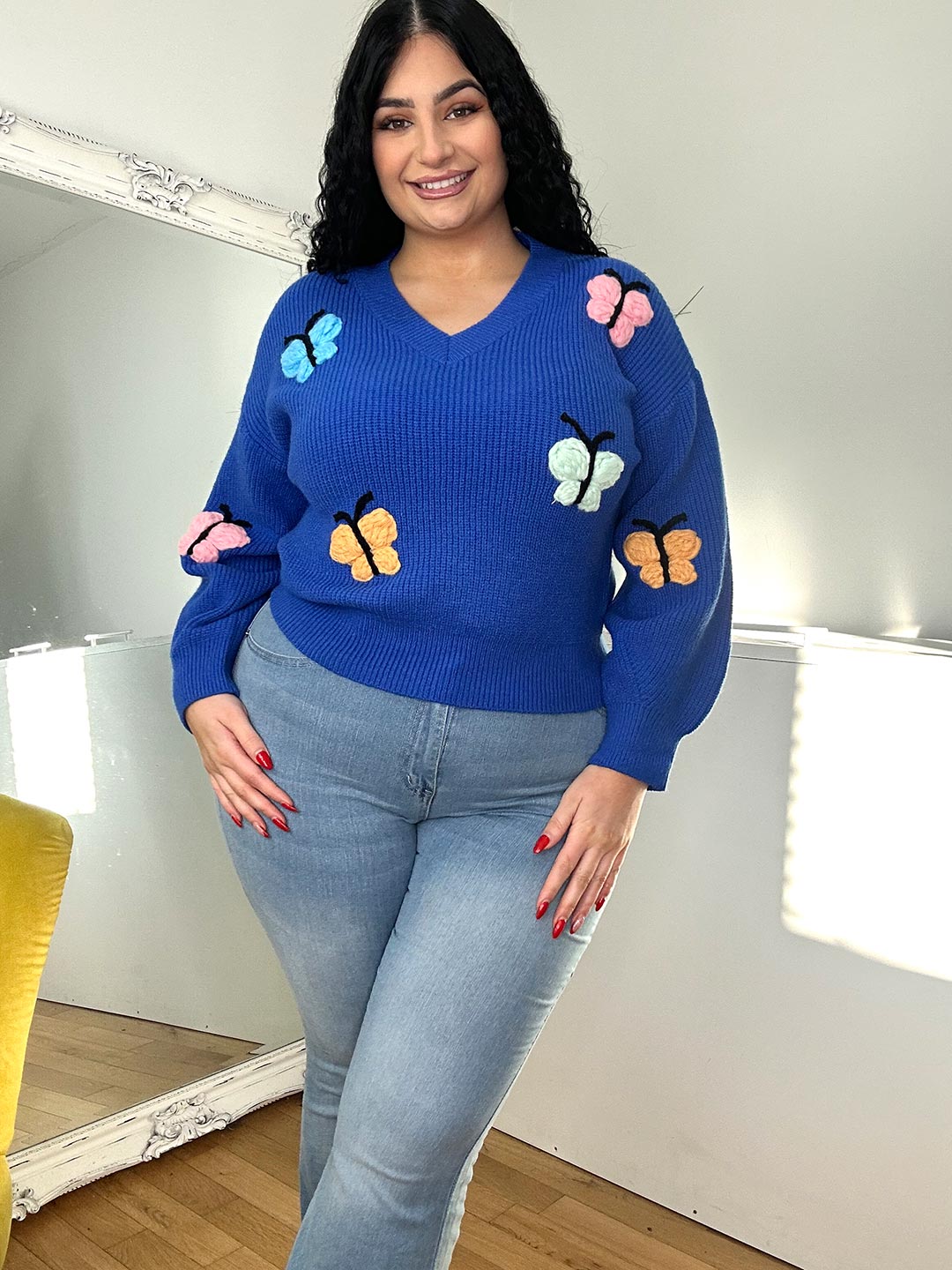 black haired girl wearing a blue jumper with butterflies print