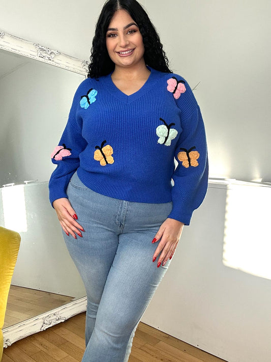 black haired girl wearing a blue jumper with butterflies print