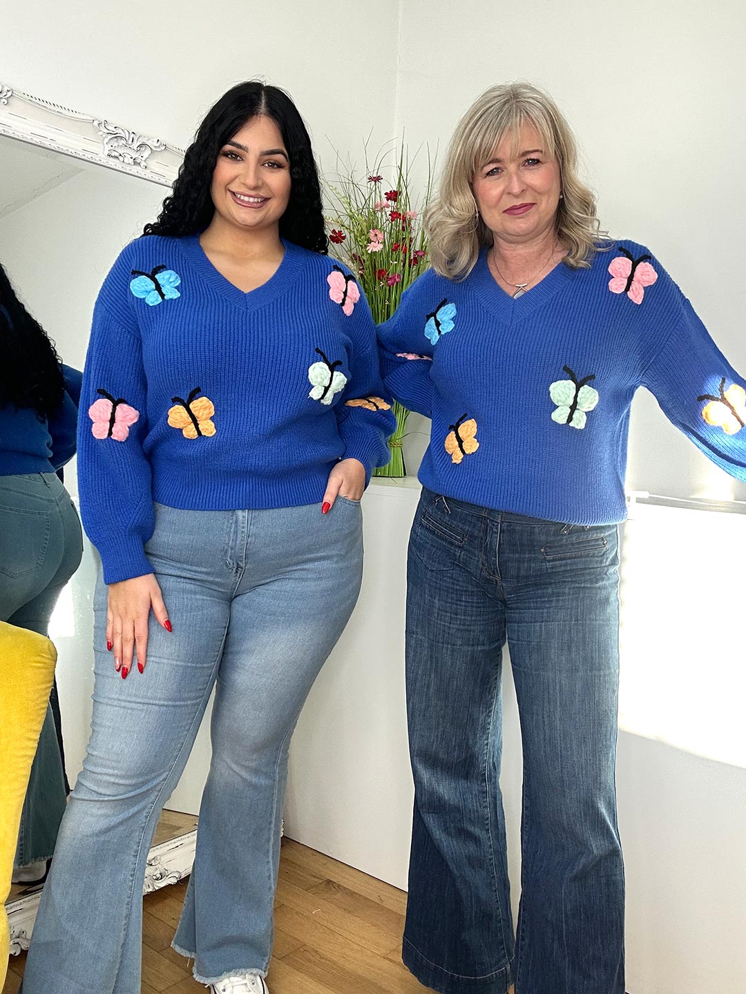 two women wearing a blue jumper with butterflies print