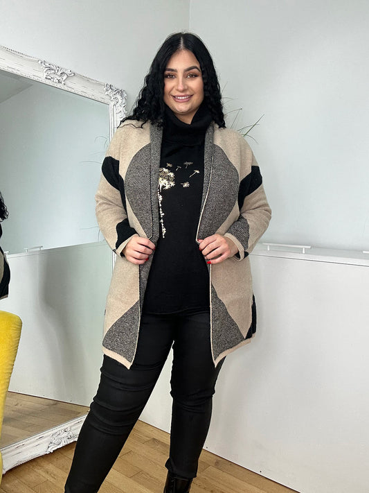  A woman with long curly black hair wearing a beige and black patterned open-front coatigan, styled with black pants and a turtleneck.