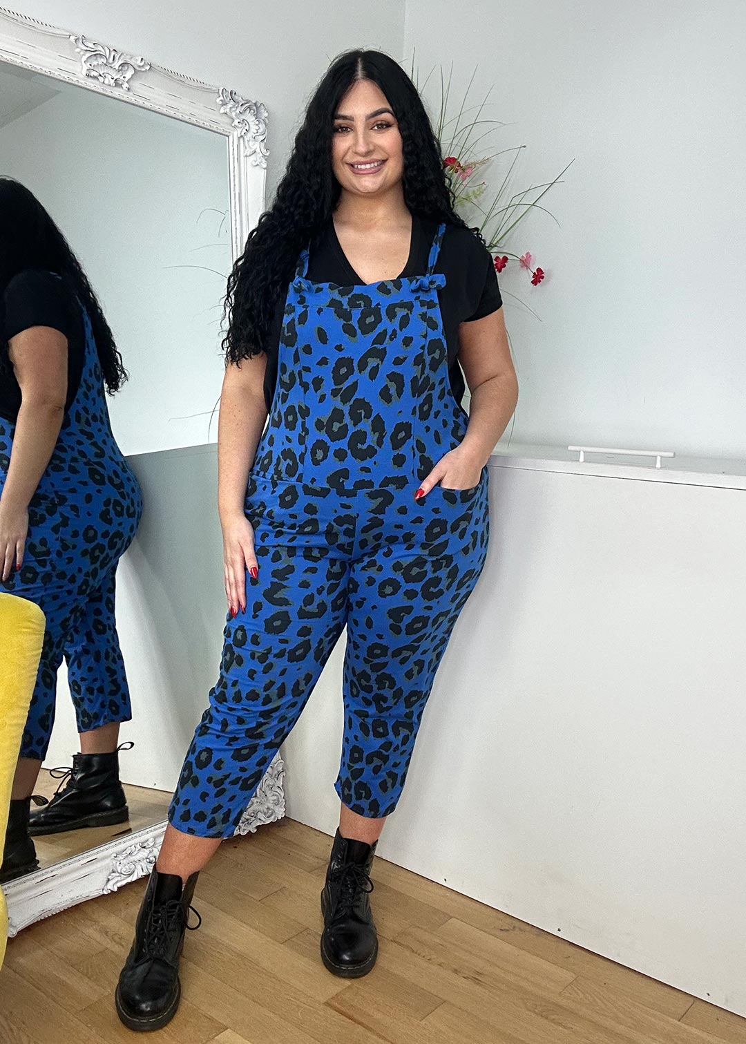 A woman in blue leopard print dungarees and a black top, highlighting a striking and contemporary outfit