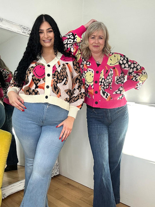 Two women wearing jeans and a stylish leopard print cardigan stands confidently, showcasing their fashionable outfits.