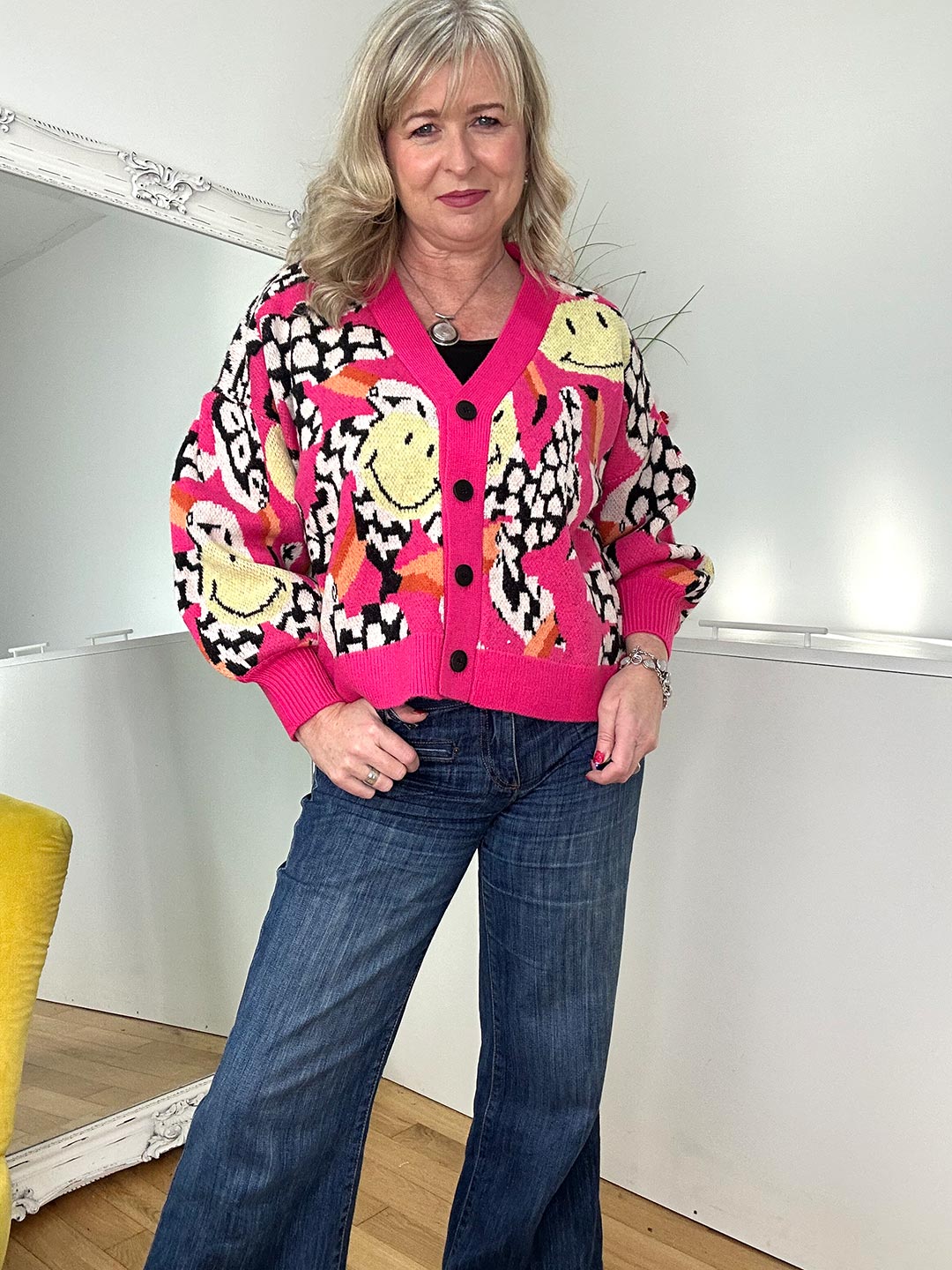 A woman wearing jeans and a stylish leopard print cardigan stands confidently, showcasing her fashionable outfit.